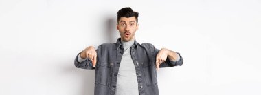 Heyecanlı adam diyor ki, vay canına, parmaklarını şaşkına çeviriyor, havalı tanıtım teklifleri sunuyor, kot ceketle beyaz arka planda duruyor..