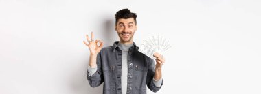 Dolarları tutan heyecanlı bir adam resmi ve mutlu yüzle işaret göster, para kazan, beyaz arka planda dur..