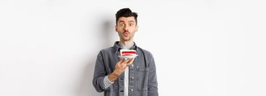 Adam doğum gününü kutluyor, pastaya mum üflüyor ve dilek tutuyor, beyaz arka planda duruyor..