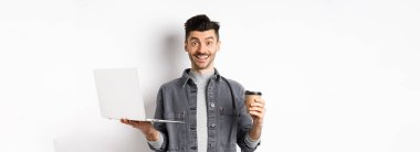 Mutlu, enerjik, kahve içen, dizüstü bilgisayarda çalışan, içkiden enerji alan, beyaz arka planda duran adam..