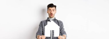 Gayrimenkul ve sigorta konsepti. Heyecanlı bir adam gazete kupürlerini gösterip 