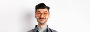 Bıyıklı, gözlüklü, kameraya bakan, gülümseyen, beyaz arka planda duran mutlu adamın yakın çekimi..