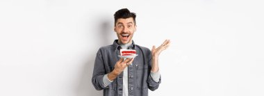 Heyecanlı bir adam doğum gününü kutluyor, mutlu görünüyor, elinde mumla pasta tutuyor, dilek tutuyor, beyaz arka planda mutlu duruyor..