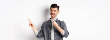 Yakışıklı adam anons yapıyor, sağ üst köşeye göz kırpıyor, logoyu gösteriyor, reklamları kontrol etmeye davet ediyor, beyaz arka planda duruyor..