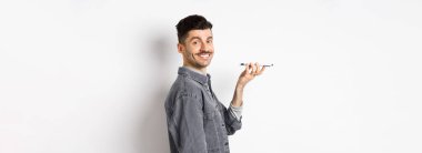 Kameraya gülümseyen bir gencin profil portresi, kelimeleri çevirmek ya da mesaj bırakmak için sesi kaydetmek, hoparlörden konuşmak, beyaz arkaplana karşı durmak..