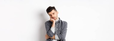 Sıkıcı ve isteksiz stil adamı kameraya duygusuz bak, sıkıcı toplantıya katıl, beyaz arka planda dur..