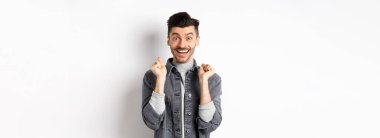 Heyecanlı ve şaşırmış adam mutlu görünüyor, ödül kazanıyor ve seviniyor, iyi haberleri duyuyor, beyaz arka planda mutlu duruyor..