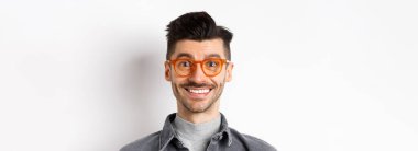 Mutlu adam yüzünün yakın portresi, şık gözlükler takıyor ve gülümsüyor, beyaz arka planda duruyor..