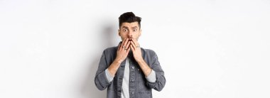 Şok olmuş, beyaz adam soluk soluğa kalmış, ağızını ellerle kapatmış ve korkunç bir şeye bakıyor, kötü bir kazaya tanık oluyor, aman Tanrım, beyaz arka planda duruyor..