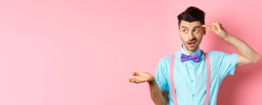 Sinirli ve şüpheci bir adam aptalca bir şeyden yakınır. Parmağını kafaya ve sola uzatır. Pembe arka planda duran garip ya da çılgın şeye bakar..