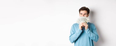 Hayalperest adam mal almayı düşünüyor, elinde para tutuyor ve dalgın dalgın bakıyor, alışveriş yapıyor, beyaz arka planda dikiliyor..