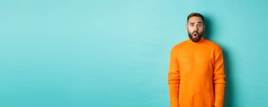 Şok olmuş ve kafası karışmış bir adam, tanıtım teklifine hayranlıkla bakıyor, turkuaz arka planda fotokopi alanının yanında duruyor..