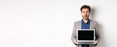 Takım elbiseli yakışıklı beyaz işadamı boş laptop ekranı gösteriyor, tanıtım yapıyor, beyaz arka planda duruyor..