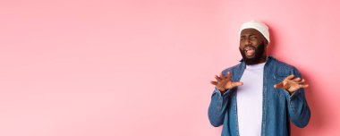 Tiksindirici, seçici siyah adam imajı rahatsız edici, kötü teklifi reddeden, nefret ve nefretle yüzünü buruşturan, pembe arka planda duran.