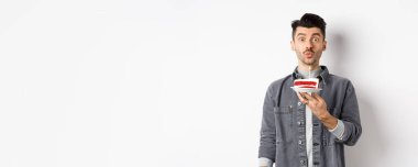 Adam doğum gününü kutluyor, pastaya mum üflüyor ve dilek tutuyor, beyaz arka planda duruyor..