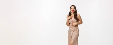 Parti ve kutlama konsepti. Zarif elbiseli, uzun boylu güzel bir kadın Noel hediyelerinin yanında duruyor, mutlu bir şekilde gülüyor, beyaz arka planda duruyor..