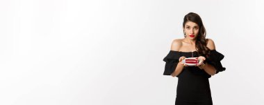 Parti ve kutlama. Siyah elbiseli nazik bir kadın doğum günü pastası veriyor. Doğum günü mumunda dilek diliyor. Beyaz arka planda duruyor..