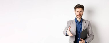 Kendine güveni tam bir işadamı. El sıkışmak için elini uzatıyor. Toplantıda iş ortaklarını selamlıyor..