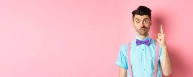 Eureka tabelasında parmağını kaldıran düşünceli bir adam sevgililer günü için hediye önerileri sunuyor, pembe arka planda duruyor..