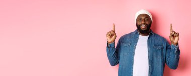 Yakışıklı, mutlu, Afro-Amerikalı bir adam. Parmakla işaret ediyor, gülümsüyor ve tanıtım teklifi sunuyor. Hippi beresi ve kot gömlek giyiyor..