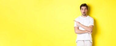 Çekici adam solu işaret ediyor, reklam teklifiyle ilgili sorular soruyor, afişi gösteriyor, sarı arka plana hayret içinde duruyor..