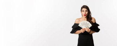 Moda ve alışveriş konsepti. Kırmızı dudaklı, heyecanlı bir kadın. Para gösteriyor ve kameraya bakıyor. Beyaz arkaplan..