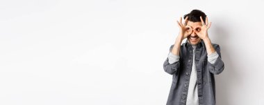 Logoya el dürbünüyle bakan gülümseyen adam, iyi bir ölüm görüyor ve tatmin olmuş görünüyor, beyaz arka planda duruyor..