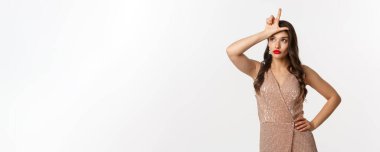 Kutlama ve parti konsepti. Kırmızı dudaklı çekici genç bir kadın, cazibeli bir elbise, alnında ezik işareti olan, cahil bakışları olan, beyaz arka planda duran.