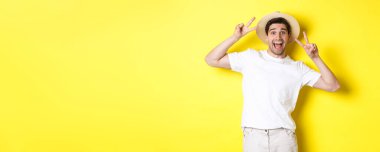 Turizm ve tatil kavramı. Barış işaretleriyle poz veren mutlu erkek turist, heyecanla gülümsüyor, sarı arka planda duruyor..