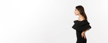 Beyaz arka planda duran zarif siyah elbiseli güzel bir kadının profil görüntüsü. Boşluğu kopyala