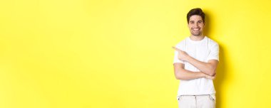 Yakışıklı adam solu işaret ediyor ve gülümsüyor, sarı fotokopi alanındaki reklamları gösteriyor..