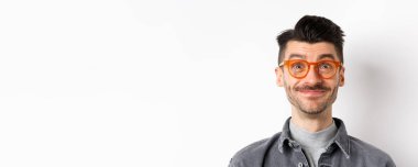 Bıyıklı, gözlüklü, kameraya bakan, gülümseyen, beyaz arka planda duran mutlu adamın yakın çekimi..