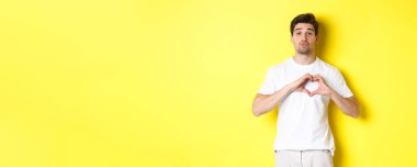 Tatlı çocuk dudaklarını büzüyor ve öpüşmeyi bekliyor, kalp hareketi gösteriyor. Aşk ve romantizm kavramı.