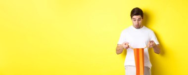 Sürpriz erkek arkadaş hediyesini açtı, içine baktı, şaşırdı, sarı arka planda durdu..