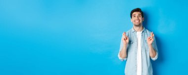 Şanslı adam dua ediyor ve dua ediyor. Dua eden yüzüyle mavi arka planda duruyor..