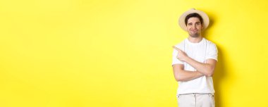 Turizm ve yaşam tarzı kavramı. Şüpheci adam şikayet ediyor, kötü bir şeyi işaret ediyor, hoşnutsuz görünüyor, sarı arka plan.