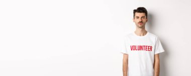 Beyaz tişörtlü, kameraya bakıp yardım etmeye hazır genç bir gönüllü..