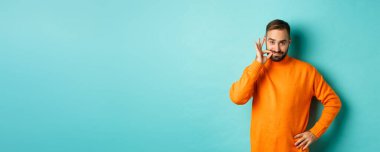 Yakışıklı sakallı adam söz veriyor ağzını kapalı tut, dudaklarını mühürle, ağzını kilitle, açık mavi arka planda dur..