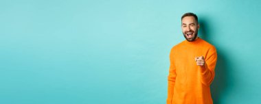 Arsız çekici adam seni tebrik ediyor, iyi işi övüyor, kameraya göz kırpıyor ve açık mavi arka planda duruyor..