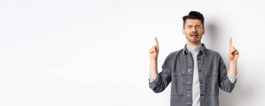 Üzgün ve sefil bir adam ağlarken parmaklarını havaya kaldırıyor, hayal kırıklığına uğramış reklamlar yapıyor, hıçkıra hıçkıra ağlıyor, beyaz arka planda duruyor..