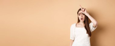 Kendine güveni tam bir kadın, ezik tabelasıyla insanlarla alay ediyor, kabalaşıyor, bej arka planda duruyor..