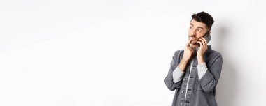 Düşünceli yakışıklı bir adamın telefon konuşması ve düşünme şekli, dışarıdan sipariş verirken seçim yapması, beyaz arka planda durması..