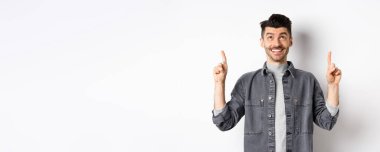 Bıyıklı neşeli beyaz adam yukarı bakıyor, gülümsüyor, hayal kuruyor, havalı bir terfi anlaşması yapıyor, beyaz arka planda duruyor..