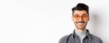 Mutlu adam yüzünün yakın portresi, şık gözlükler takıyor ve gülümsüyor, beyaz arka planda duruyor..