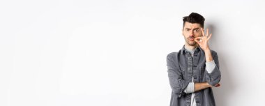 Ciddi adam fermuar hareketi yapıyor, çenesini kapalı tutmasını söyle, kaşlarını çatsın ve dudaklarını mühürlesin, beyaz arka planda dursun..