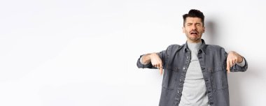 Üzgün, ağlayan, ağlayan, hıçkıra hıçkıra ağlayan, üzücü haberler veren, beyaz arka planda kot ceket giyen adam..