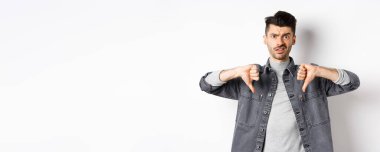 Hayal kırıklığına uğramış bir adam beyaz arka planda duran, kötü bir şeye şüpheyle bakan, hoşlanmayan ve onaylamayan bir adam..