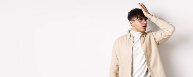 Sinirli stil sahibi bir adamın portresi, aptal bir şeyden gözlerini devirmek, beyaz arka planda durmak, yorgun..