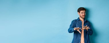 Adam korkunç ve kötü bir şeyden korkup kaçıyor, kötü ofisten reddediyor, tiksinmiş görünüyor, mavi arka planda duruyor. Boşluğu kopyala