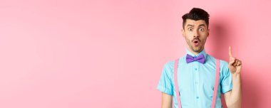 Yaratıcı adam bir fikir sunuyor, parmağını kaldırmış telkin ediyor, pembe arka planda duruyor..